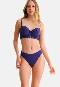 Ensemble de lingerie violet comprenant un soutien-gorge balconnet avec des bordures en dentelle, un soutien-gorge sous fil et un bas de bikini taille haute côtelé assorti.