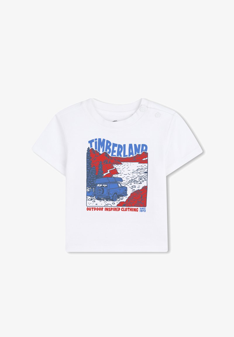 T-shirt en coton blanc avec une impression graphique d'un véhicule tout-terrain bleu, des montagnes rouges, des arbres et le texte "Timberland Outdoor Inspired Clothing".
