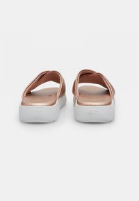 Sandale slip-on cu un exterior metalic de culoare roz aurie și o talpă platformă albă. Designul prezintă bretele încrucișate și un finisaj neted, lucios.