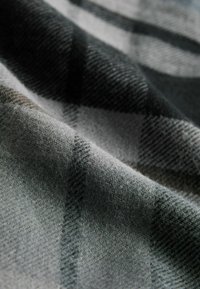 Grijs en zwart geblokt stof met een zachte textuur, met een geweven patroon en een golfachtige hang.
