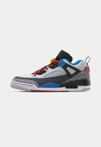 Sneaker med hvid læder og grå mesh, med røde, blå og gule accenter. Inkluderer en mønstret grå ydersål og sort mellemsål.