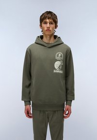 Sudadera color verde oliva con un bolsillo tipo canguro, puños y dobladillo acanalados. Presenta tres impresiones gráficas blancas en la parte delantera. Tejido suave y texturizado.