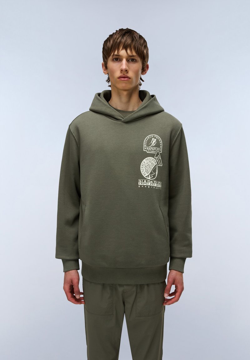 Sudadera color verde oliva con un bolsillo tipo canguro, puños y dobladillo acanalados. Presenta tres impresiones gráficas blancas en la parte delantera. Tejido suave y texturizado.