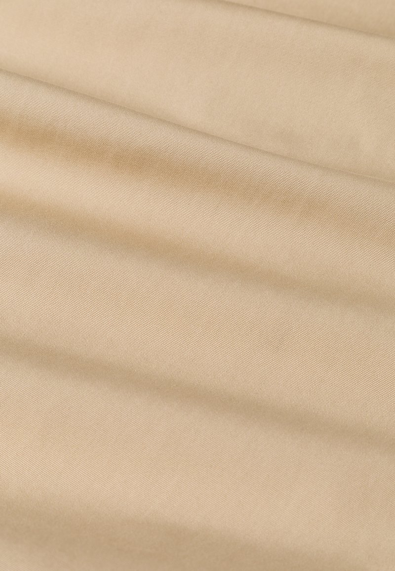 Beiger Stoff mit glatter Textur, der einen subtilen Glanz und ein gleichmäßiges Webmuster aufweist, sanft in weichen Falten drapiert.