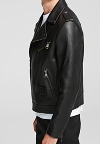 Svart läderbikerjacka med sned framtida dragkedja, flera fickor, kviltade axelapplikationer och en figursydd design.