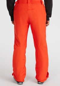 Heldere oranje skibroek met een gladde textuur, losse pasvorm, versterkte stiksels en ritsen bij de manchetten voor verstelbare breedte.