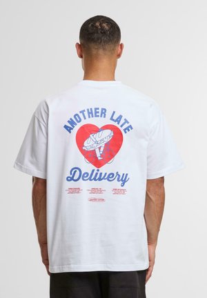 White cotton t-shirt featuring a graphic on the back with a red heart, bicycle, and the text "ANOTHER LATE Delivery" in blue.