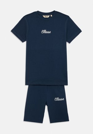 Granatowy zestaw koszulki i szortów z bawełny z haftowanym logo "Ellesse". Koszulka ma okrągły dekolt; szorty są do kolan.