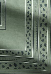 Zielona tkanina z wzorem zawierającym ciemnoniebieskie akcenty, paski oraz kwiatowe motywy na krawędziach. Gładka tekstura.