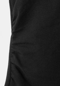 Gros plan sur un tissu noir extensible avec un subtil détail froncé le long de la couture latérale.