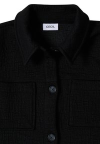 Black textured button-up shirt with pointed collar and two chest pockets, brand label "CECIL" inside the collar.