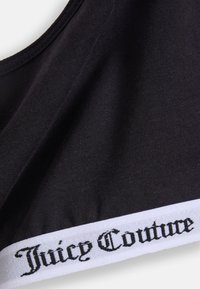 Čierny športový podprsenka vyrobená z hladkej látky. Má biely elastický pás s nápisom "Juicy Couture" v štýlovom čiernom písme.