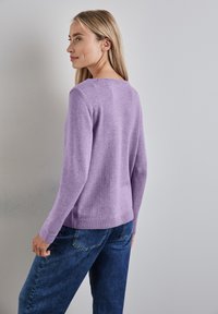 Maglione a maglia di un delicato viola chiaro con maniche lunghe, orlo a coste e scollatura rotonda, abbinato a jeans in denim blu.