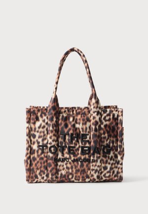 Sac fourre-tout imprimé léopard avec deux anses et texte noir ""THE TOTE BAG MARC JACOBS"" sur le devant.