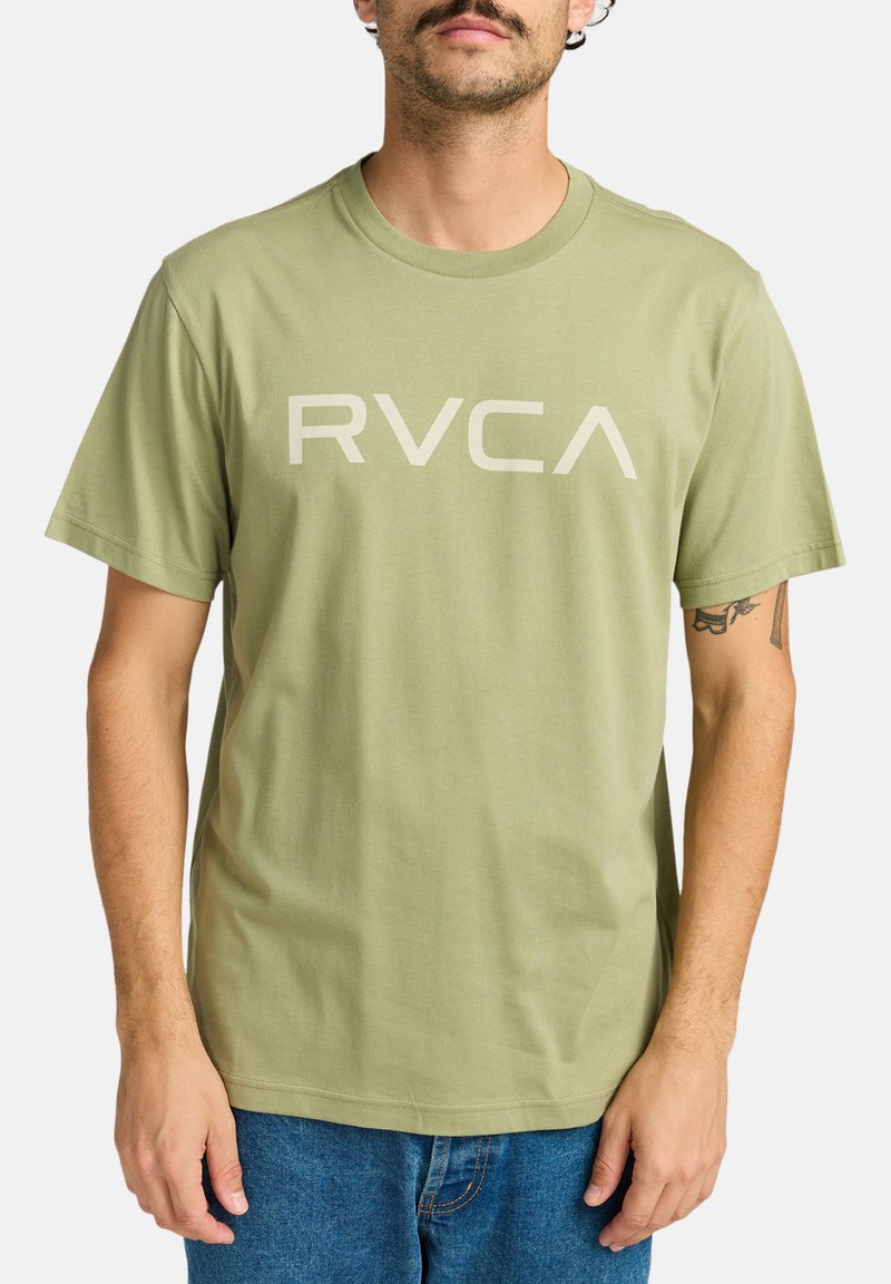 Oliven grøn bomulds t-shirt med et stort lysegrå "RVCA" logo på forsiden. Korte ærmer og en afslappet pasform.