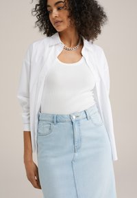 Valge nööbiga särk, mille all on valge ribatud tank top, kombinatsioonis helesinise teksaseelikuga. Riietust kaunistab hõbedane kettkaelakee.