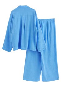 Svetlo modrý, textúrovaný dvojdielny outfit, ktorý obsahuje košeľu s dlhým rukávom a golierom a široké nohavice s elastickým pásom.