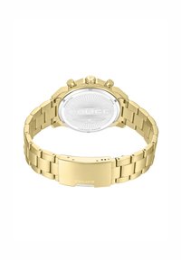 Ura iz zlato toniranega kovinskega materiala z zapestnim trakom v povezani zasnovi in okroglo srebrno številčnico. Ima tri potisne gumbe in vgravirano znamko "POLICE".