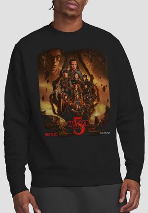 Black sweatshirt featuring a detailed "Stranger Things 5" poster with main characters, Netflix logo, and "The Finale" text.