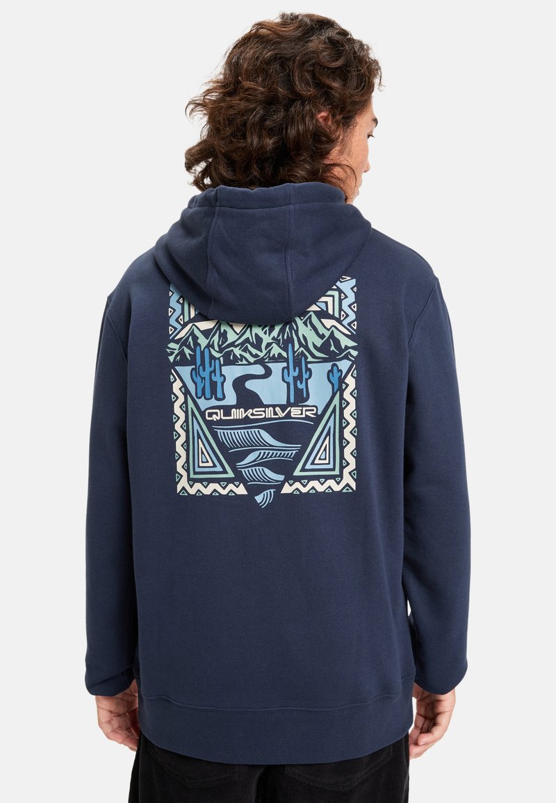 Sudadera azul marino con un gran gráfico colorido en la parte posterior que presenta montañas, cactus y patrones geométricos. Textura de tela suave.