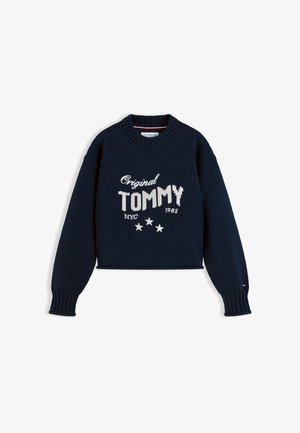Mørkeblå strikket sweater med ribstrikkede ærmekanter og krave, hvid tekst med teksten "Original TOMMY NYC 1985," og tre hvide stjerner under teksten.
