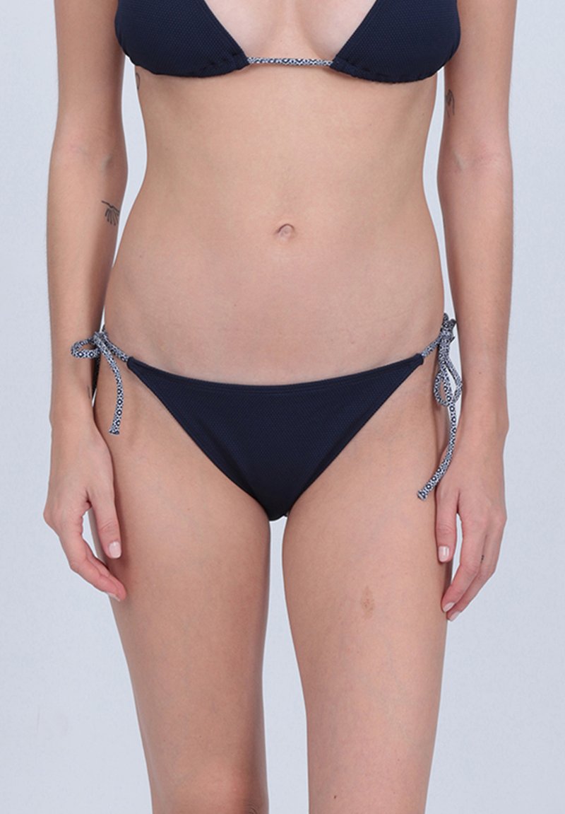 Bikini bleu marine avec un tissu texturé, comprenant un haut triangulaire et un bas à nouer sur les côtés avec des accents de ficelle à motif.