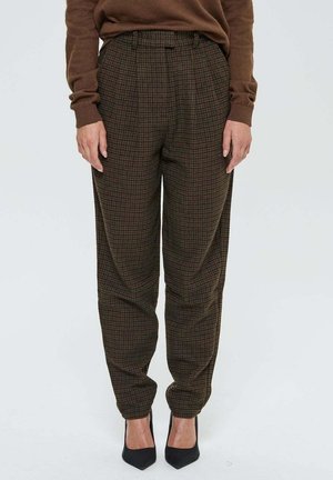 Pantalons taille haute à carreaux marron avec une coupe ample, dotés de plis et de poches latérales, associés à des escarpins noirs à bout pointu.