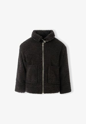 Musta sherpa fleece -takki, jossa on korkea kaulus, etuvetoketju ja kaksi suurta läppätaskua valkoista taustaa vasten.