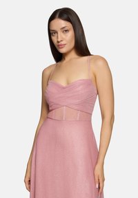 Rosa Kleid mit einem taillierten Oberteil, das ein geschichtetes, transparentes Design aufweist. Der Rock fließt elegant und ist aus einem glitzernden Material gefertigt, das Textur hinzufügt.