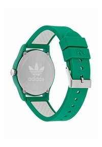 Orologio con cinturino in silicone verde, caratterizzato da un retro in acciaio inossidabile, un logo distintivo e accenti bianchi; cassa rotonda con finitura texturizzata.