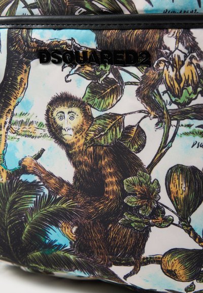 Singe à fourrure brune assis sur une branche d'arbre entourée de feuilles vertes et de fruits, logo noir "DSQUARED2" au-dessus.