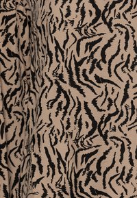 Tessuto con una base beige e un audace motivo a strisce nere a tigre. Texture morbida con colori in contrasto e linee dinamiche e fluide.