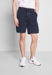 Shorts cargo bleu marine avec taille à cordon, deux poches latérales et une poche patch sur la jambe, fabriqués en tissu léger.