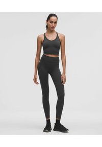 Sötét szürke sportos szett, amely egy rövid fazonú, vékony pántos toppból és magas derekú leggingsből áll. Simaság és testhezálló kialakítás jellemzi.