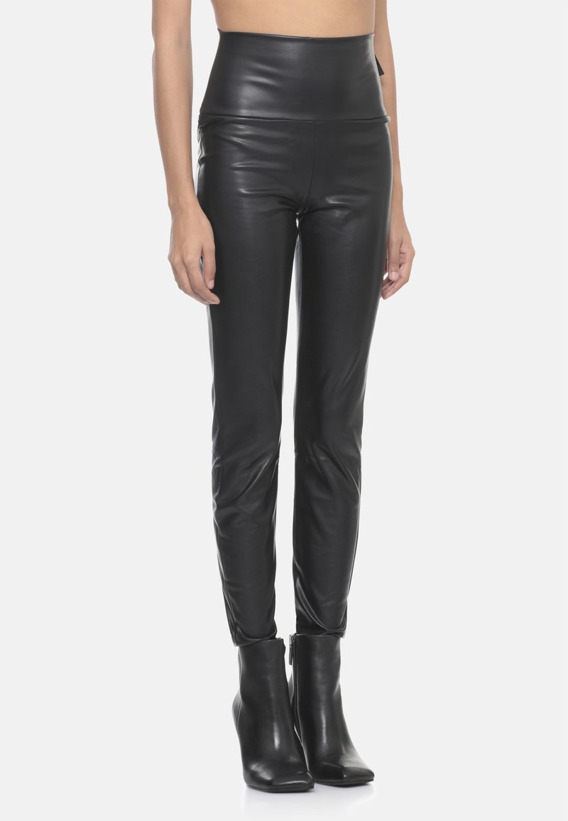 Pantaloni in pelle neri a vita alta con finitura liscia, design aderente e taglio alla caviglia, abbinati a stivaletti neri con tacco.