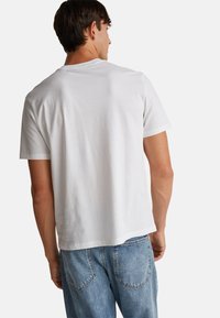 Bílý bavlněný tričko s kulatým výstřihem a krátkými rukávy. Volný střih s hladkým povrchem a žádnými viditelnými vzory nebo akcenty.