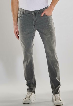 Graue Denim-Jeans mit geradem Schnitt, ausgestattet mit einem Knopfverschluss, fünf Taschen und dezenten Verwaschungen. Kombiniert mit weißen Sneakers.