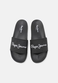 Sandalias deslizantes negras con una tira ancha que presenta números en relieve y el logo "Pepe Jeans" en blanco. Textura suave, diseño minimalista.