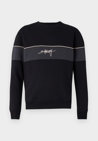 Sudadera negra con cuello redondo acanalado, mangas largas y una franja horizontal gris en contraste. Presenta un logo blanco en cursiva. Tejido suave.