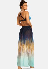 Dwuczęściowy kostium kąpielowy z kolorowym wzorzystym topem i długą, przezroczystą spódnicą w gradientzie od ciemnoniebieskiego do jasnego akwamaryny.