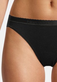 Schwarze Baumwoll-Tanga-Unterwäsche mit einem weichen, elastischen Bund und minimaler Bedeckung, die eine glatte Textur und keine sichtbaren Muster aufweist.