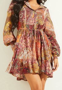 Robe à manches longues boutonnée avec un motif cachemire aux couleurs chaudes. Comprend une taille nouée, un ourlet à volants et une coupe décontractée.