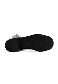 Semelle de chaussure noire avec une surface texturée, des bords lisses et une finition mate. Présente un léger talon et un dos renforcé pour la durabilité.