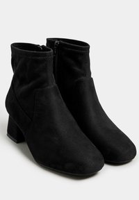 Botas de tobillo de ante negro con tacón cuadrado, que presentan una cremallera lateral y un acabado suave y texturizado. Punta redondeada y un ajuste ceñido alrededor del tobillo.