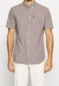 Camicia a maniche corte con bottoni in un motivo a scacchi rosso, bianco e nero. Presenta una tasca sul petto e un design con colletto classico.