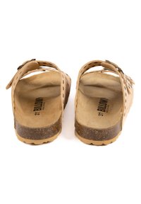 Sandales en cuir marron avec un design perforé, boucle ajustable et semelle en liège profilée. Texture lisse et forme arrondie.