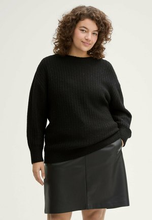Zwart gebreid sweater met ribbeltextuur, ronde halslijn en oversized fit, gecombineerd met een zwarte leren rok.