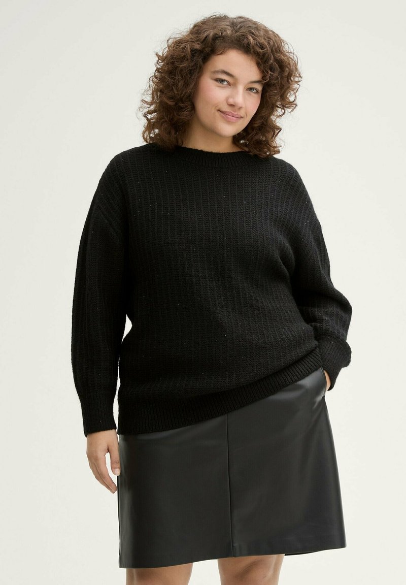 Zwart gebreid sweater met ribbeltextuur, ronde halslijn en oversized fit, gecombineerd met een zwarte leren rok.