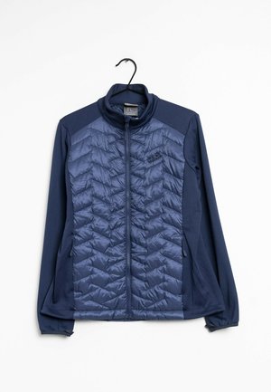 Chaqueta azul marino con cremallera completa, panel delantero acolchado y mangas de tela suave, colgada de una percha negra sobre fondo blanco.