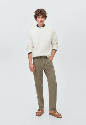 Witte sweatshirt, olijfgroene broeken en bruine sandalen. Casual fit met textuurstof. Eenvoudig ontwerp zonder zichtbare patronen of accenten.